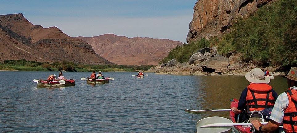 Group canoeing between dramatic mountains